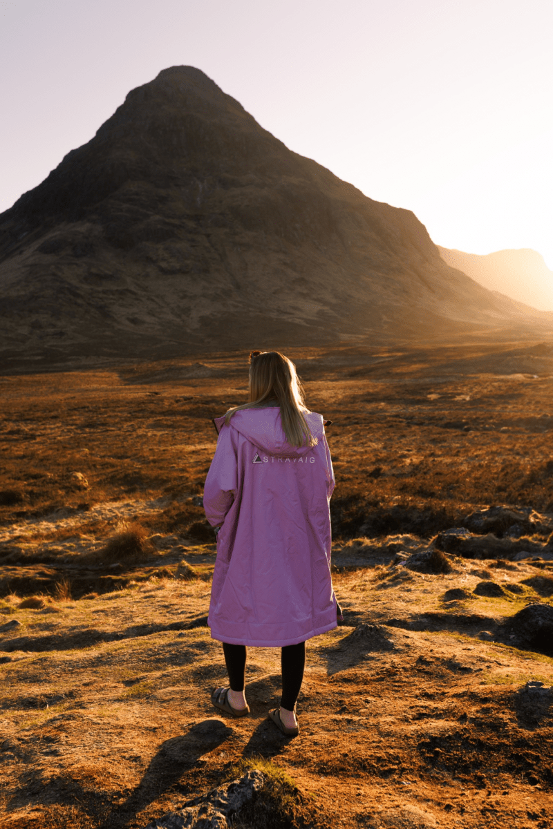 Woman in a lilac Stravaig changing robe standing in the sun with a mountain in the background