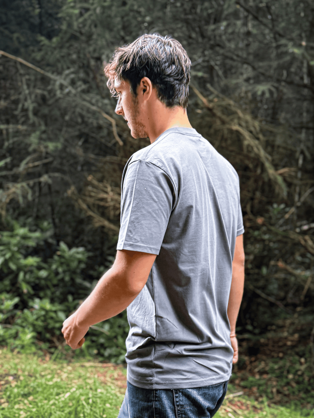 Side view of a man walking through woodland in the Haar Grey Stravaig Everyday Trail T-Shirt