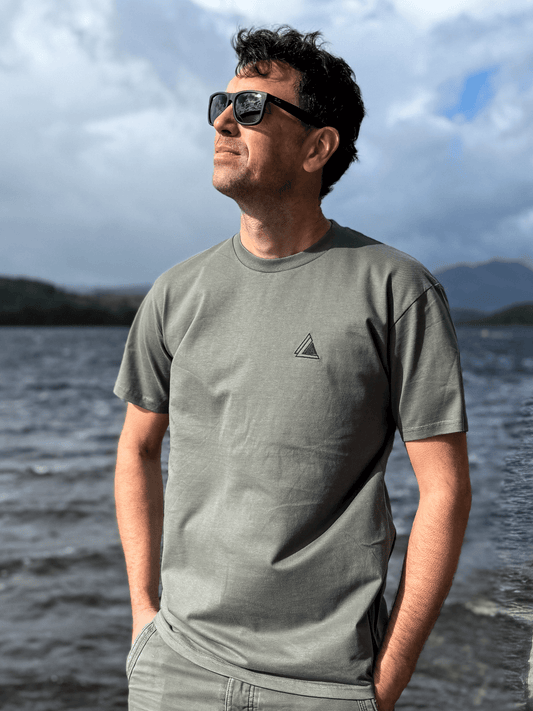 Man in sunglasses wearing the Highland Moss Stravaig t-shirt beside a loch