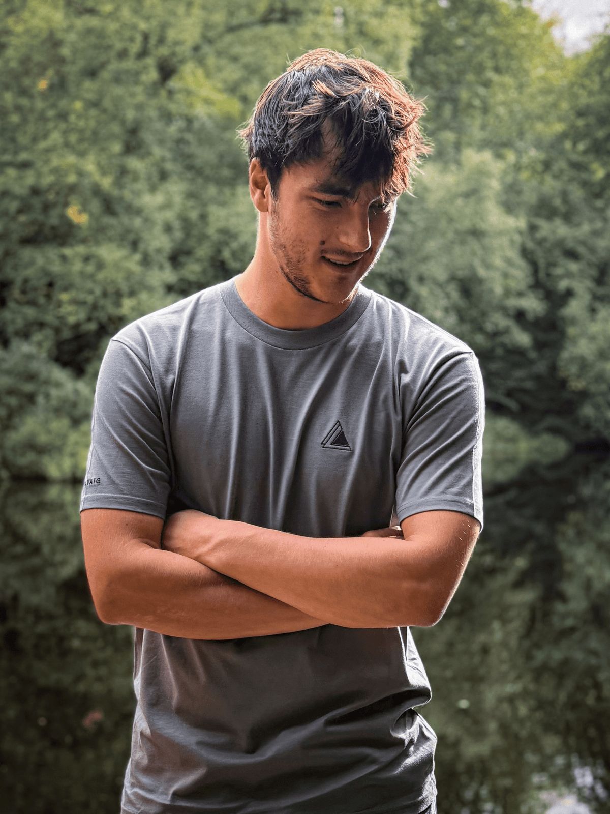 Man with arms folded wearing the Haar Grey Stravaig t-shirt among trees