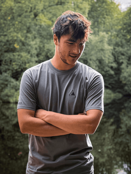 Man with arms folded wearing the Haar Grey Stravaig t-shirt among trees