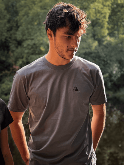 Man in a Haar Grey Stravaig t-shirt standing in dappled woodland light