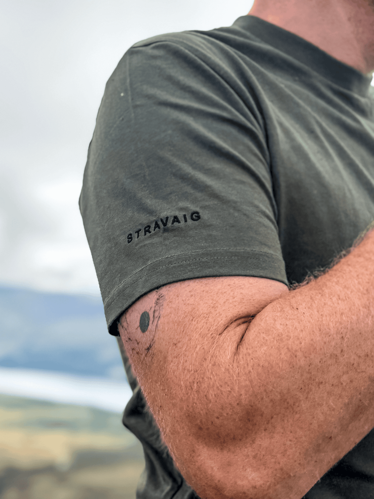 Close-up of the Stravaig sleeve print on the Highland Moss mens t-shirt with hills behind