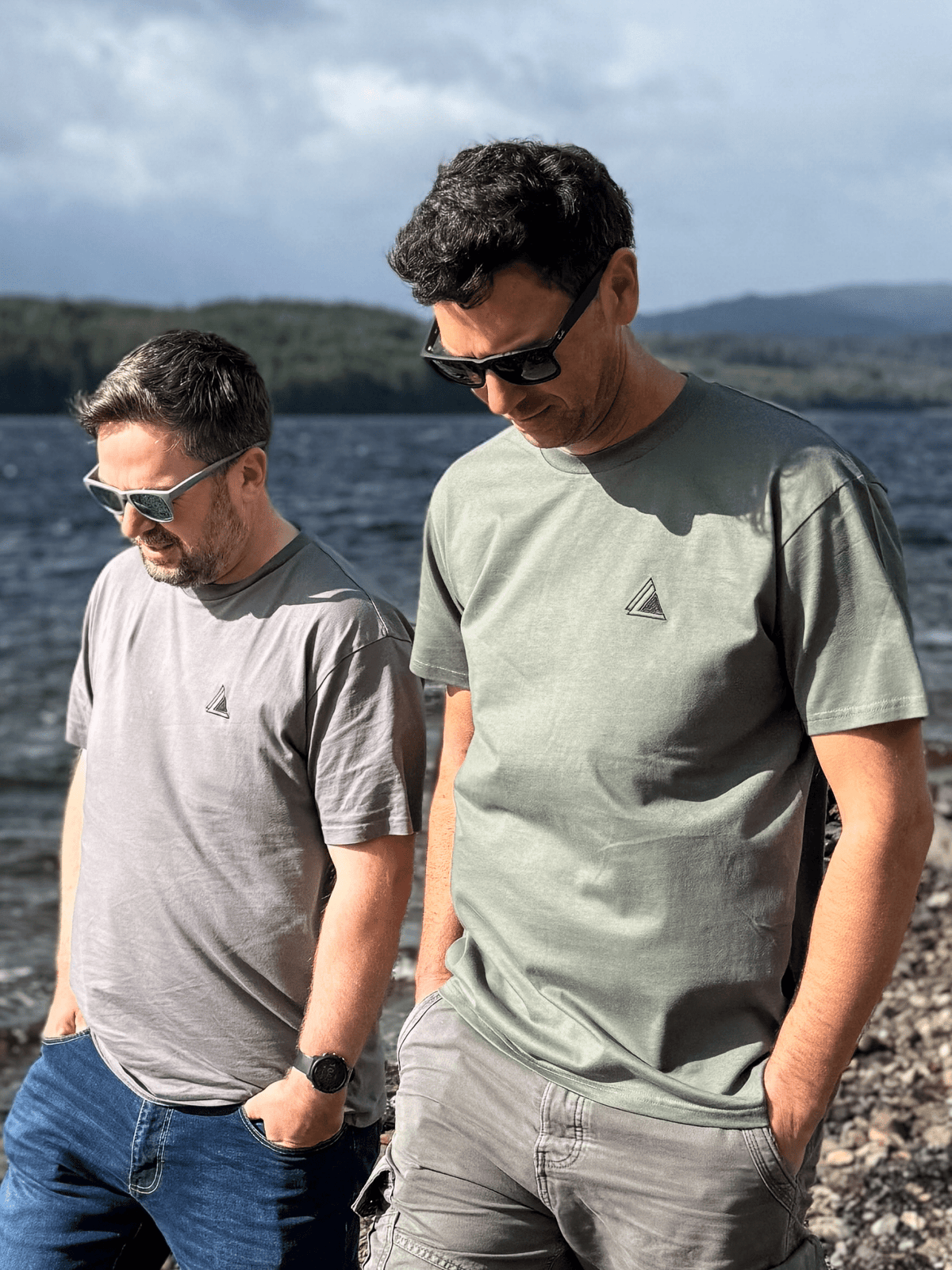 Two men walking along a loch shore in Stravaig Everyday Trail T-Shirts in Highland Moss and grey
