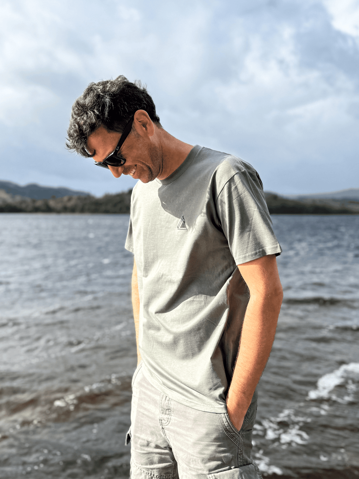 Man looking down at the loch shore wearing the Stravaig Mens Everyday Trail T-Shirt in Highland Moss