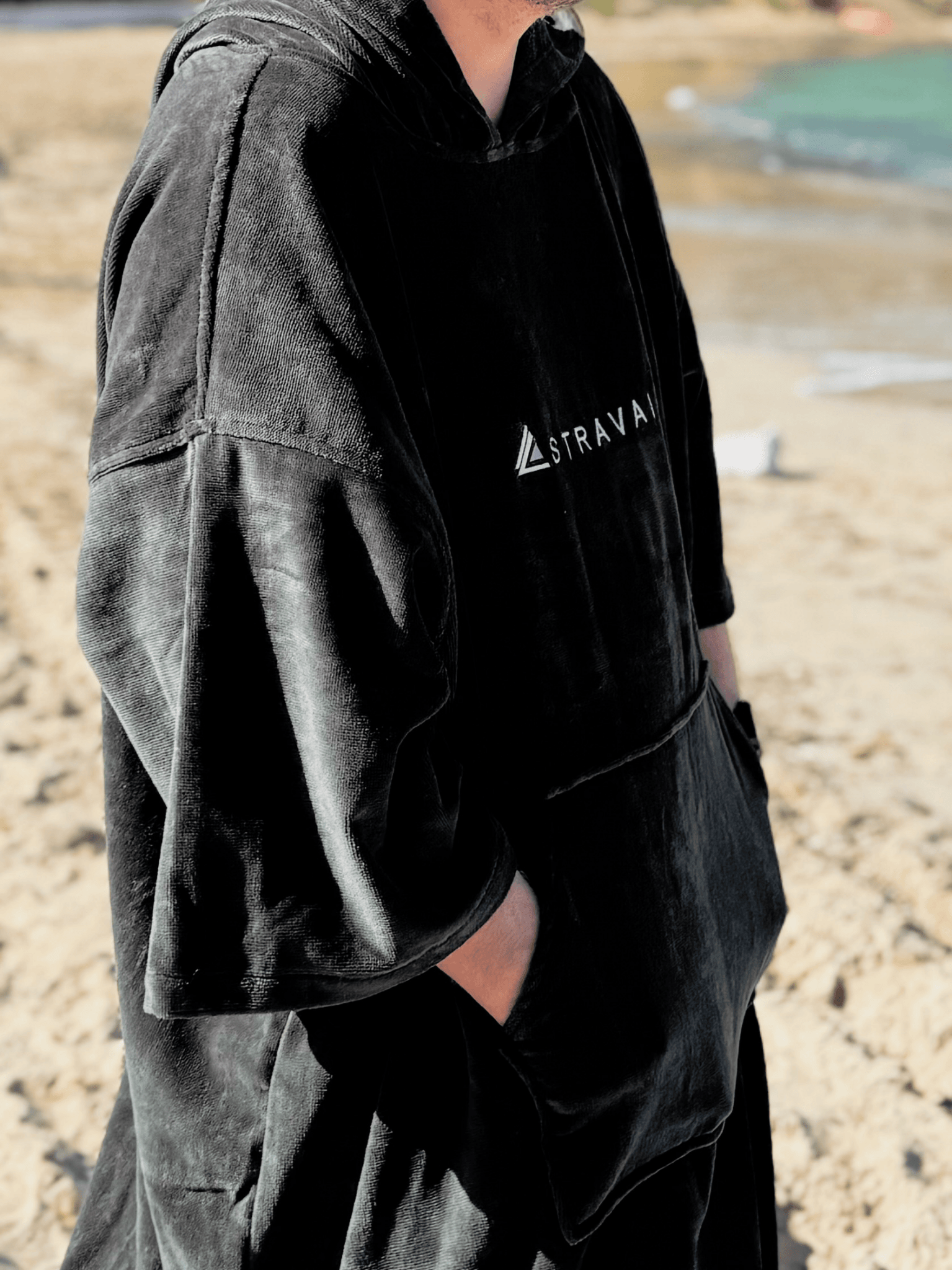 Person wearing a Sgàil Grey changing robe towel outdoors on the beach