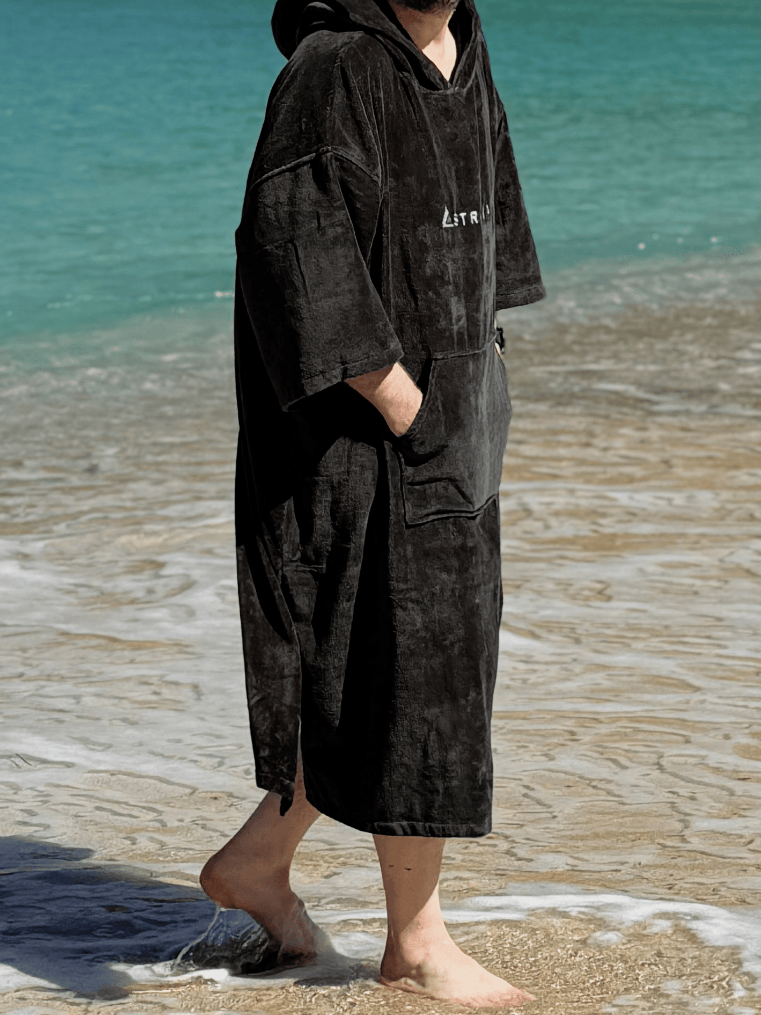 Person wearing a Sgàil Grey Stravaig Adult Hooded Towel Poncho Changing Robe on a beach