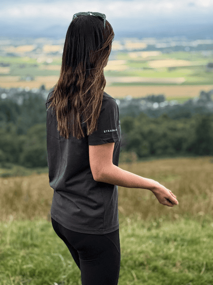Back view of a woman in a Sgàil Grey Stravaig t-shirt looking out over the Scottish countryside